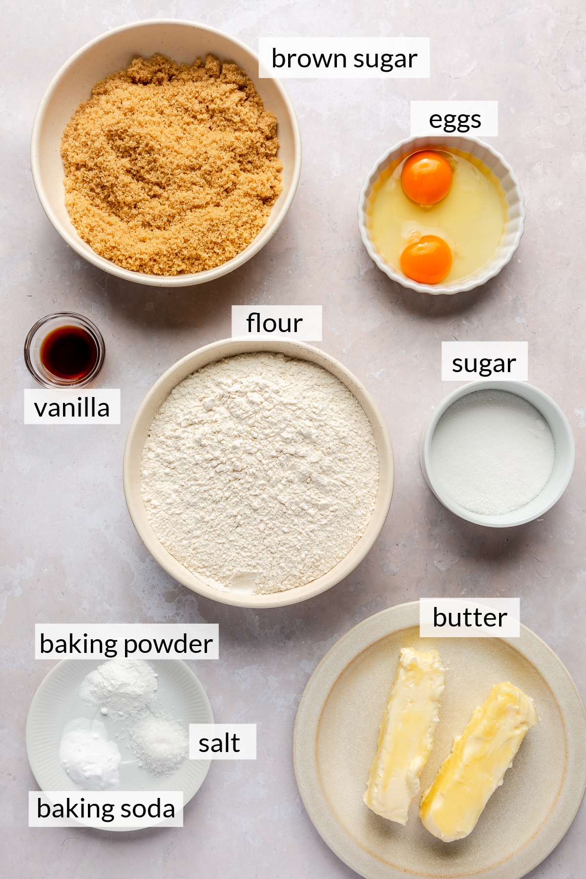 Flour, butter, sugar, eggs and vanilla divided into small bowls.