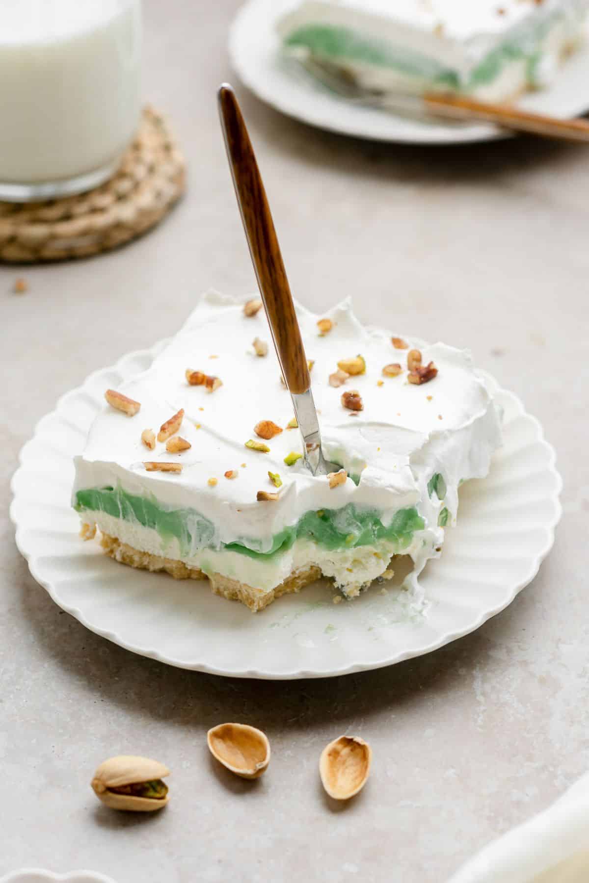 Slice of pistachio dessert with a fork in it.