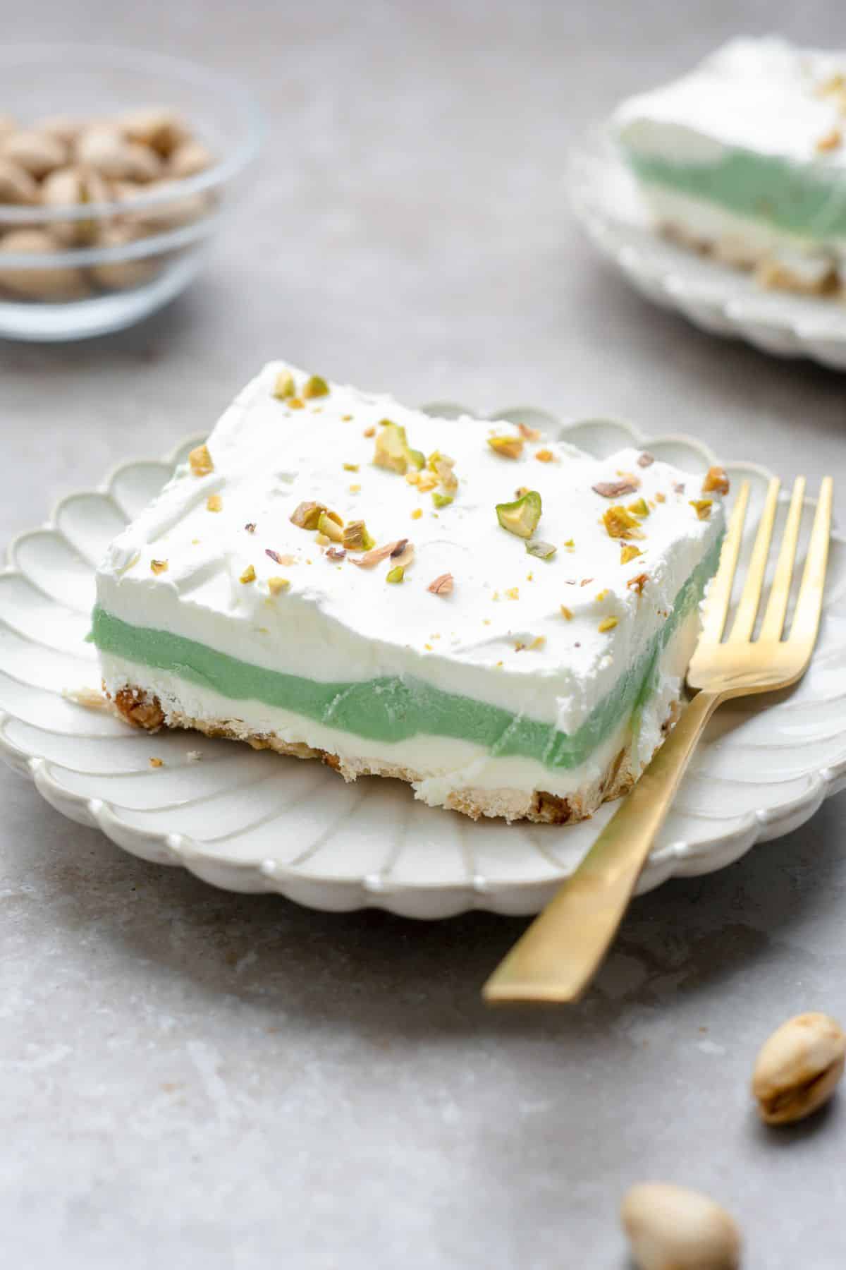 Pistachio dessert on a white plate with a fork.
