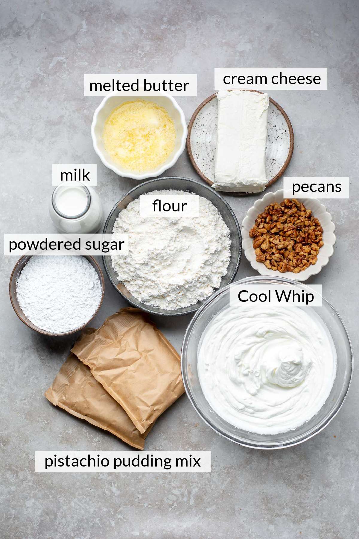 Packets of pudding mix, bowls of melted butter, milk, pecans, powdered sugar, flour and cream cheese.