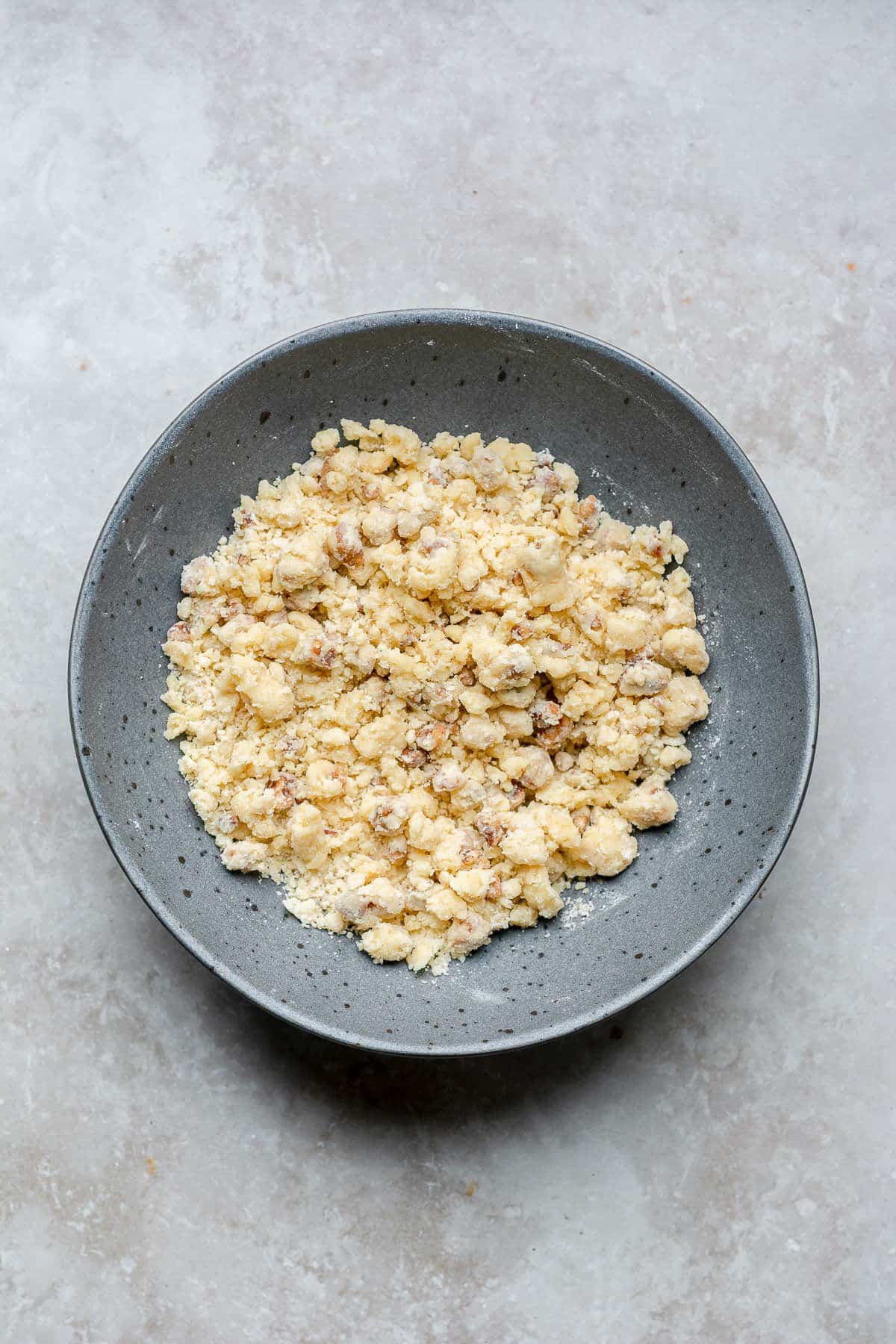 Mixing butter with flour and pecans in a bowl.