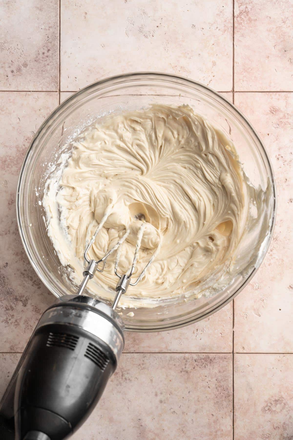 Using a hand mixer to beat cream cheese with sugar and lemon juice.