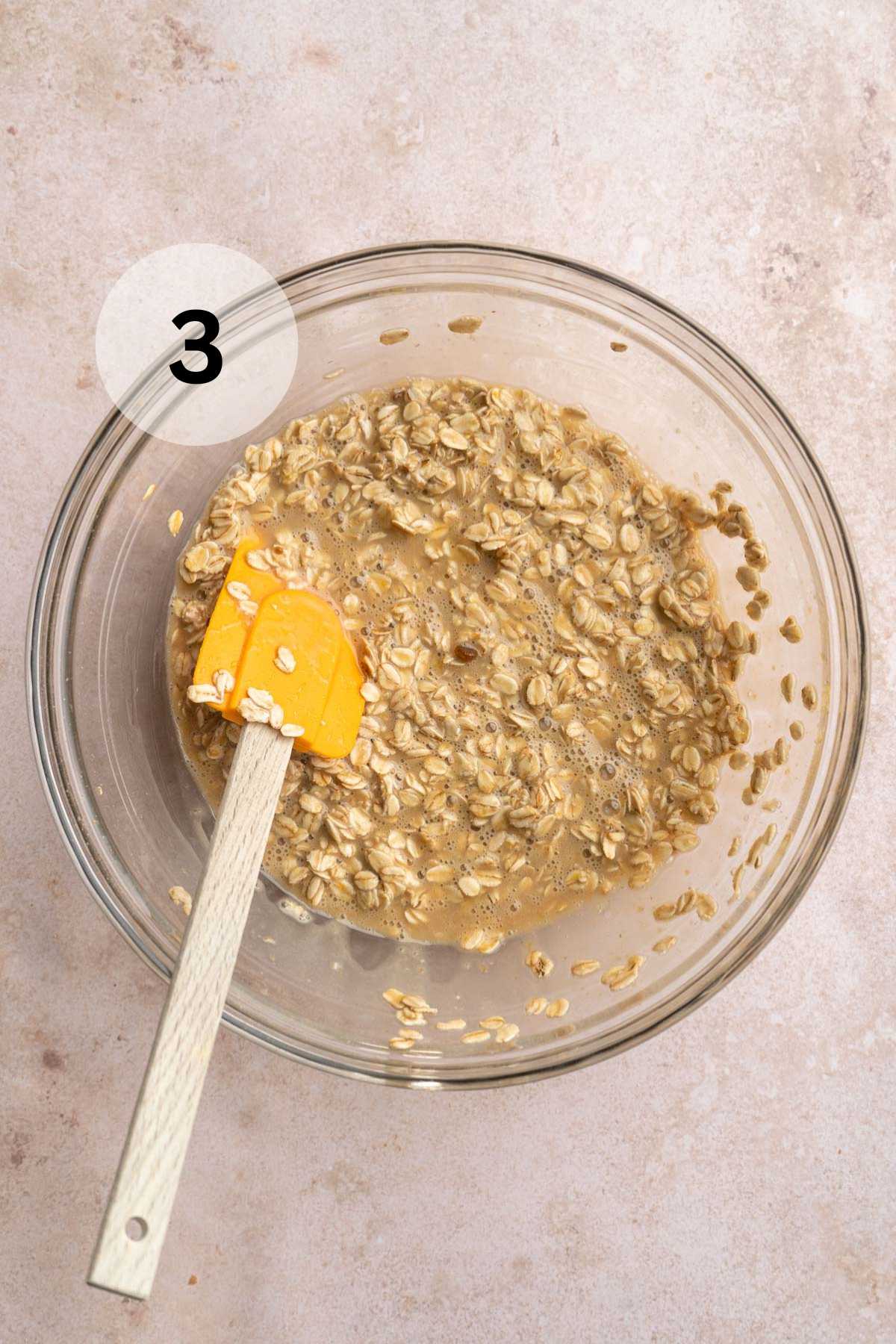 Stirring oats with milk, eggs, oil and brown sugar in a glass bowl.
