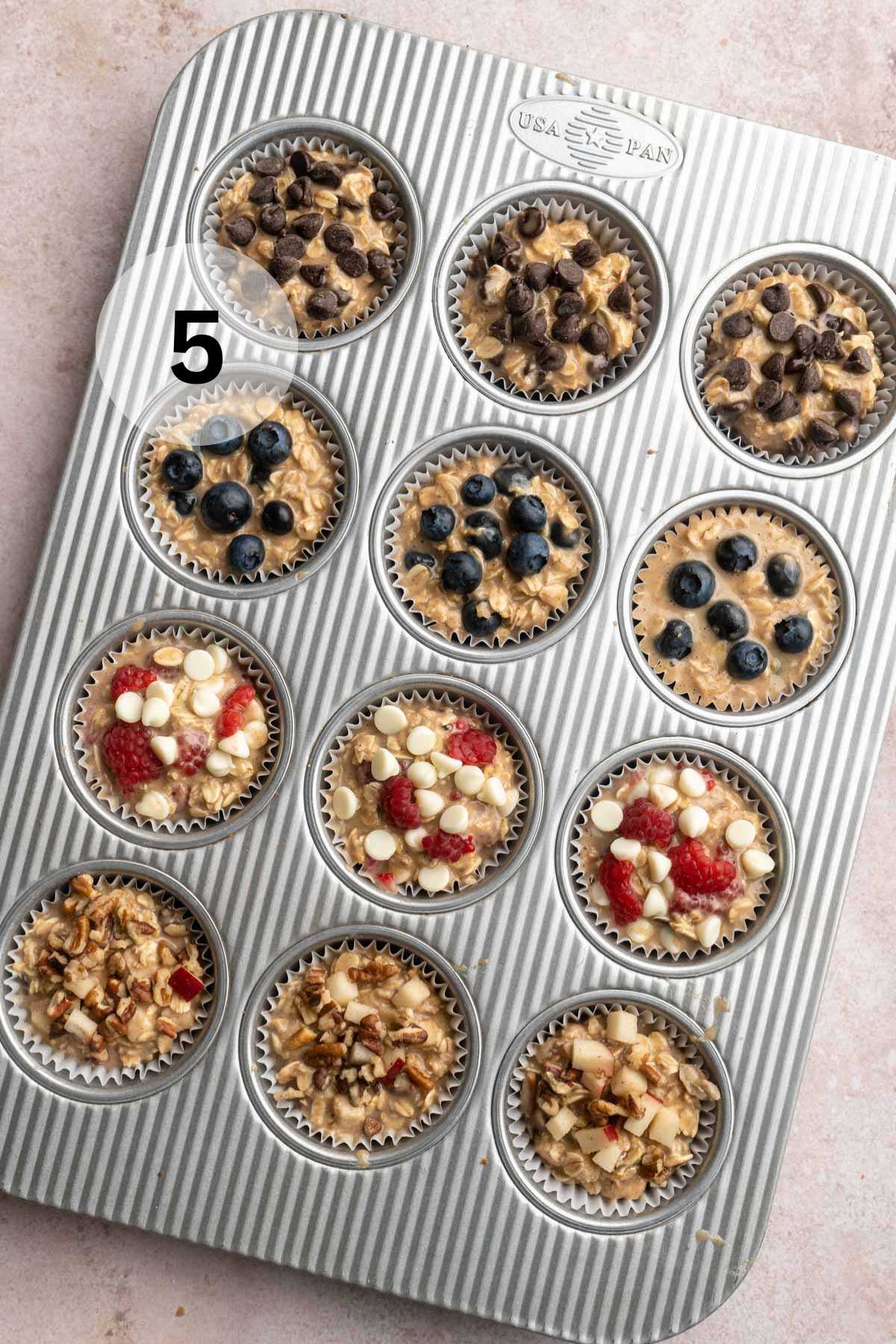 Muffin batter divided in a muffin pan and toppings added to the tops.