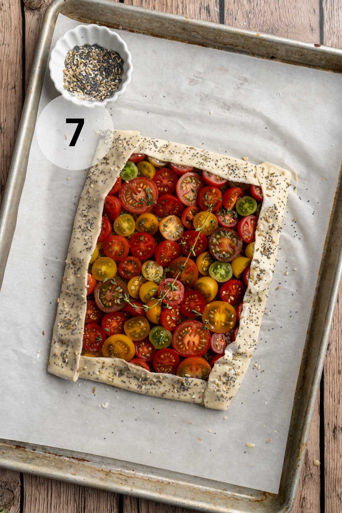 Unbaked tomato tart on a parchment lined sheet pan.