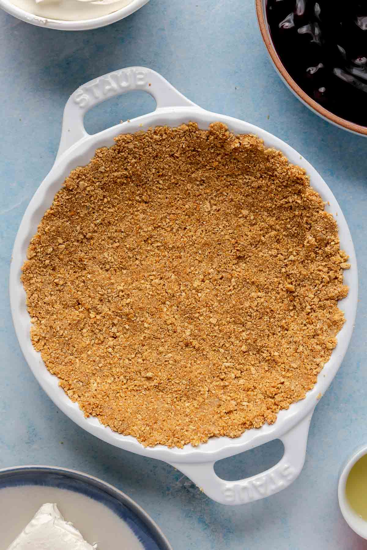 Graham cracker crust pressed into a round white dish.