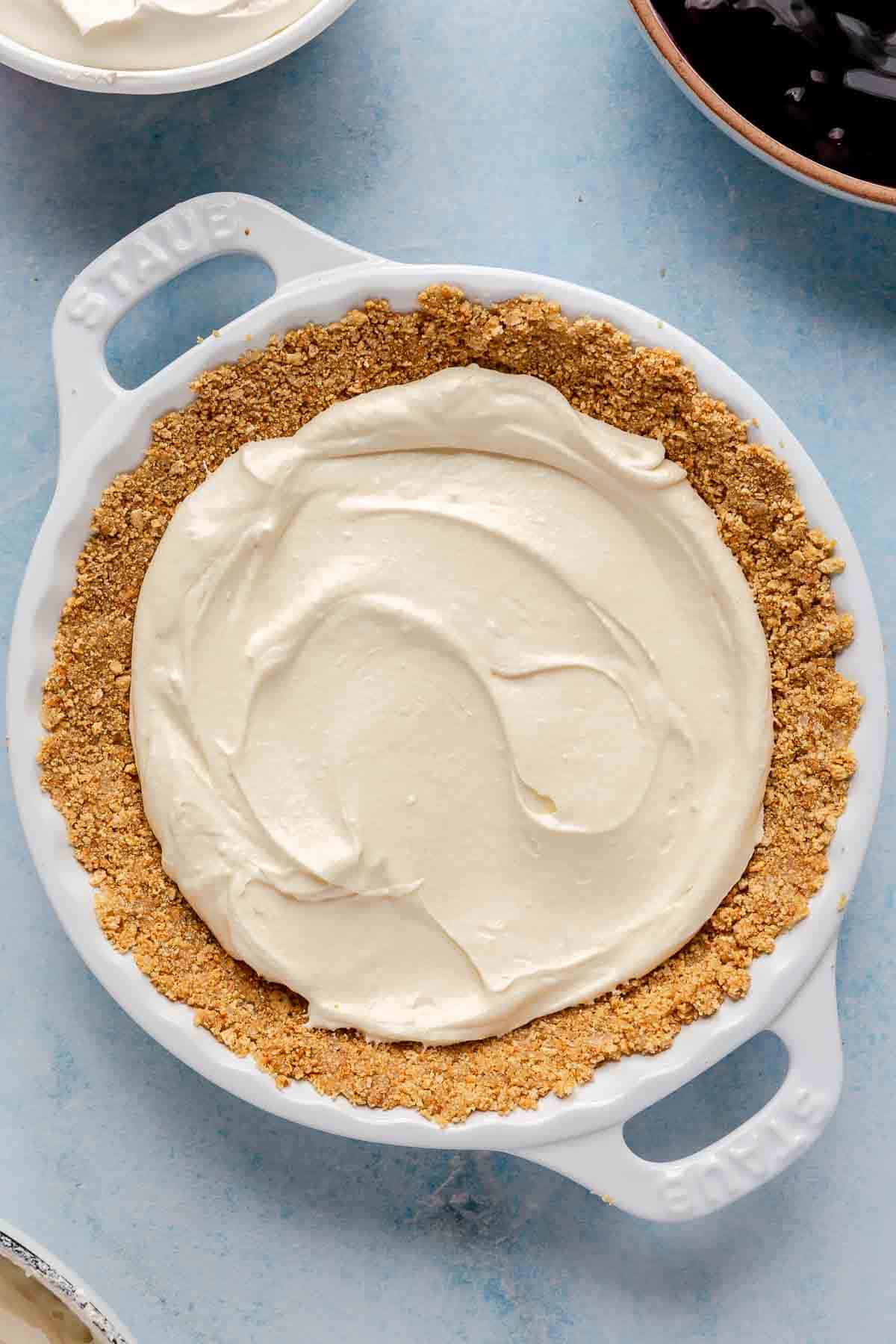 Cheesecake filling spread over graham cracker crust.