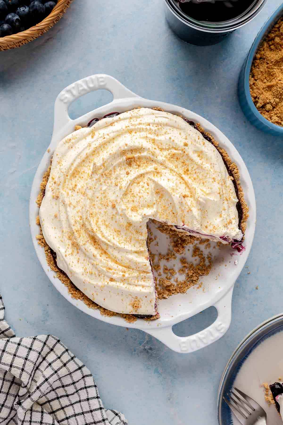 Blueberry dessert topped with Cool Whip and graham cracker crumbs with one slice missing.