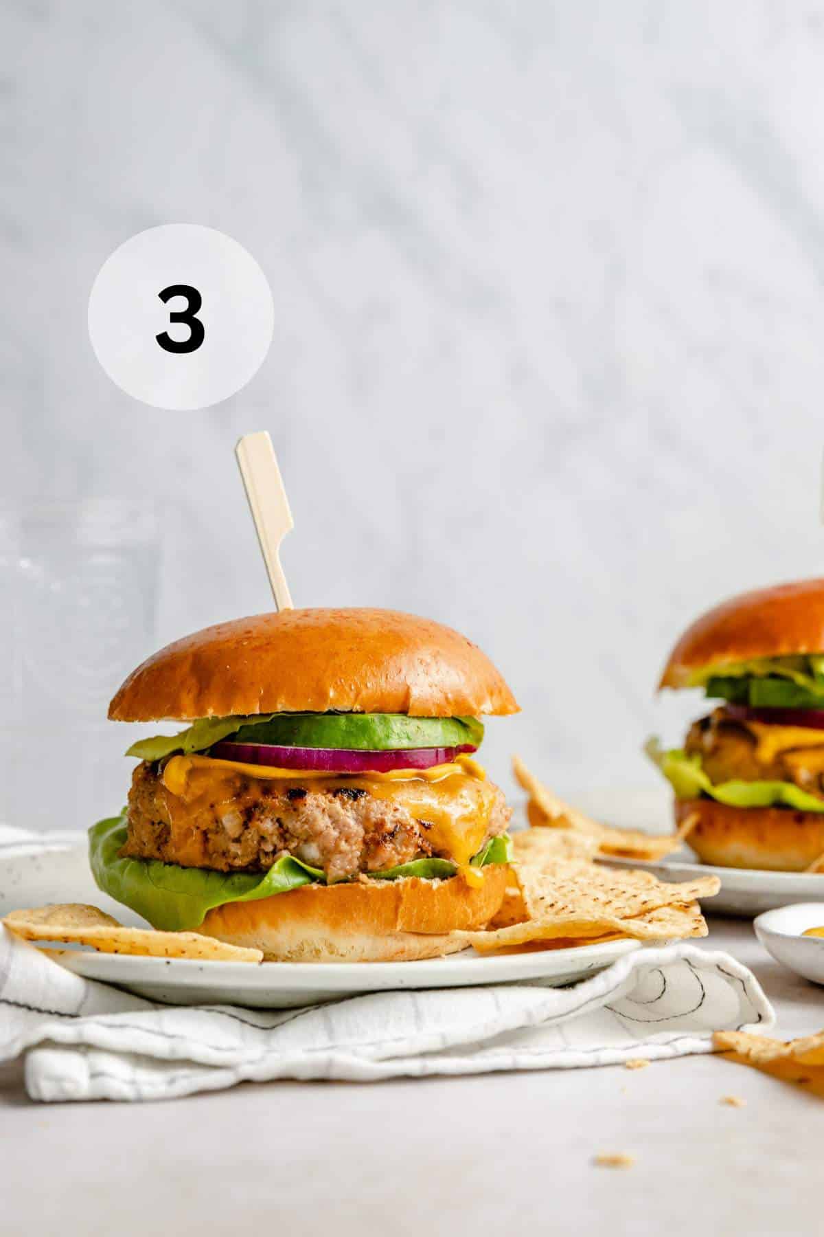 Chicken burgers served with tortilla chips on plates.