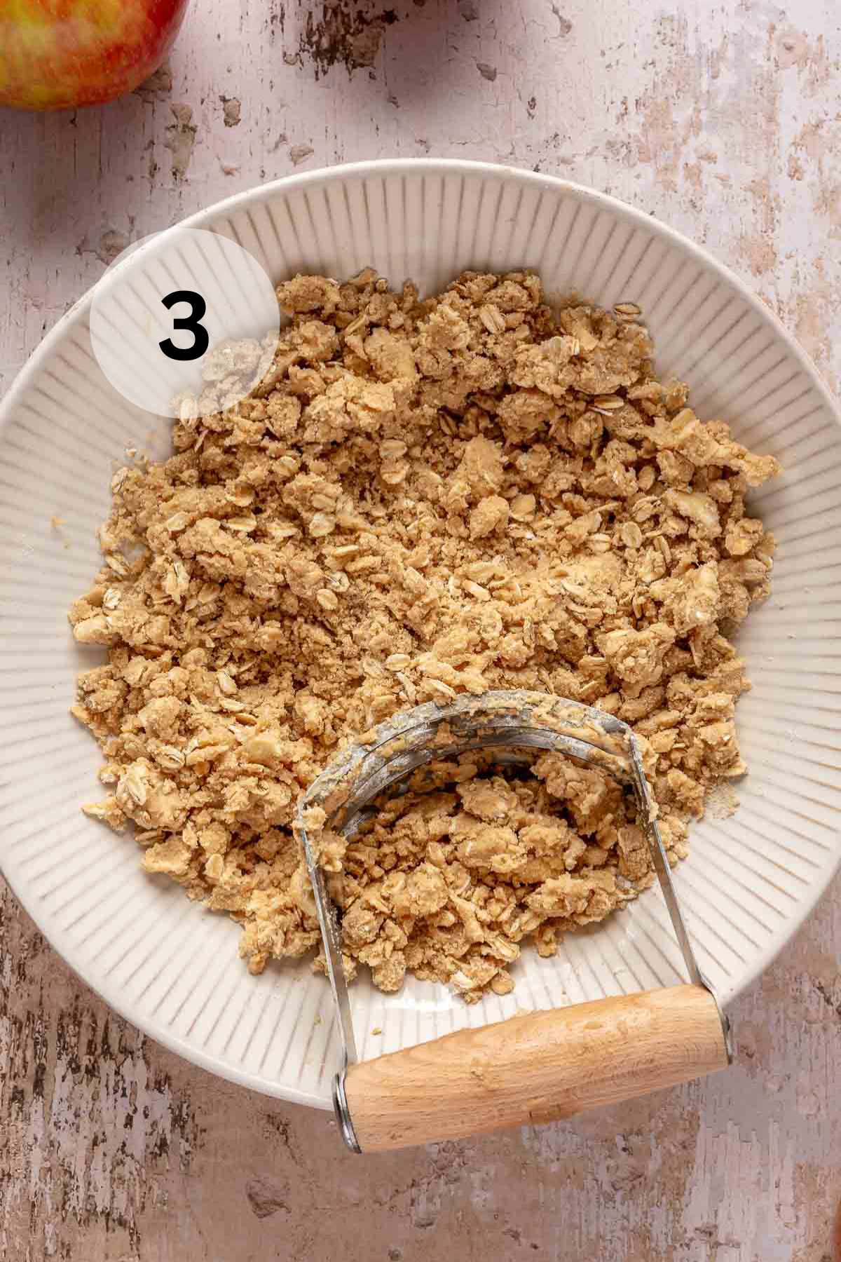 Using a pastry blender to cut butter into oat and flour mixture.