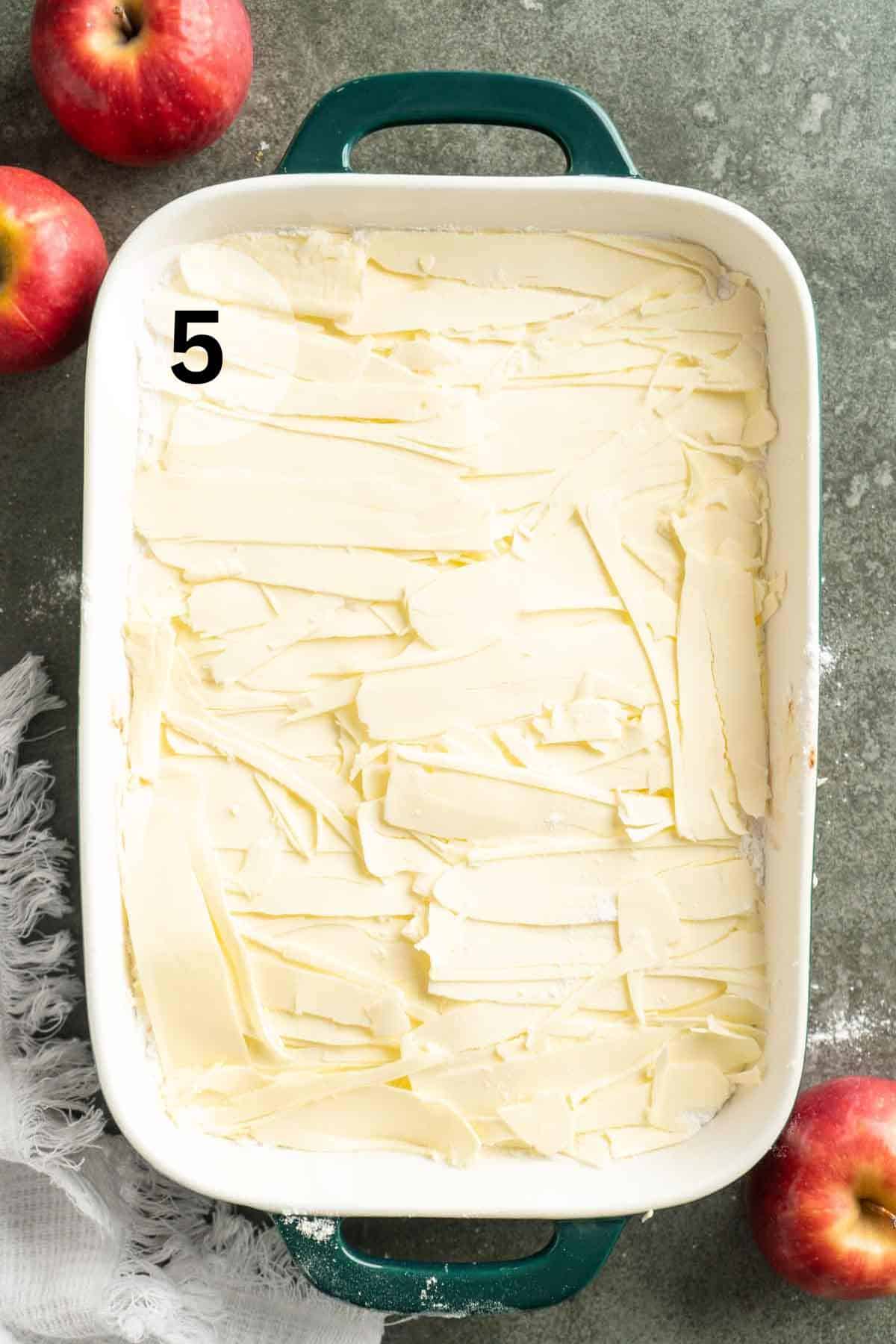 Slices of butter covering apples and dry cake mix.