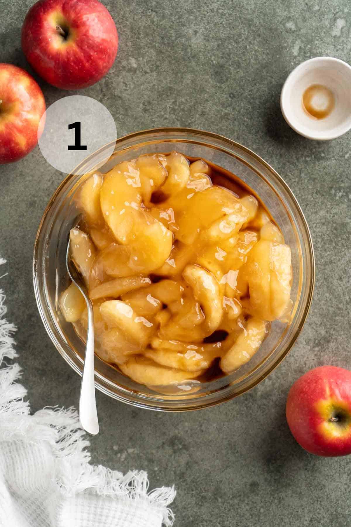 Stirring apple slices with vanilla in a small glass bowl.