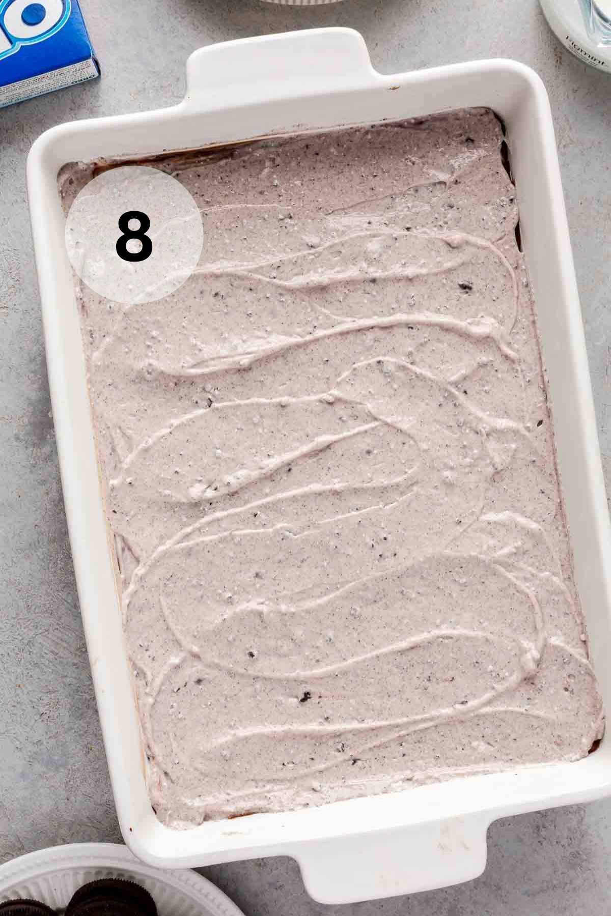 Oreo pudding spread over a chocolate pudding in a dish.