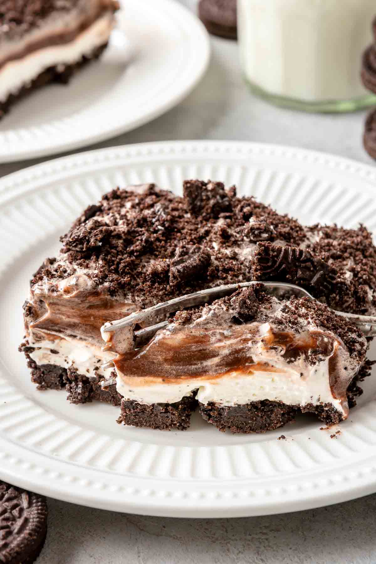 Serving of Oreo dessert on a white plate with a fork in it.