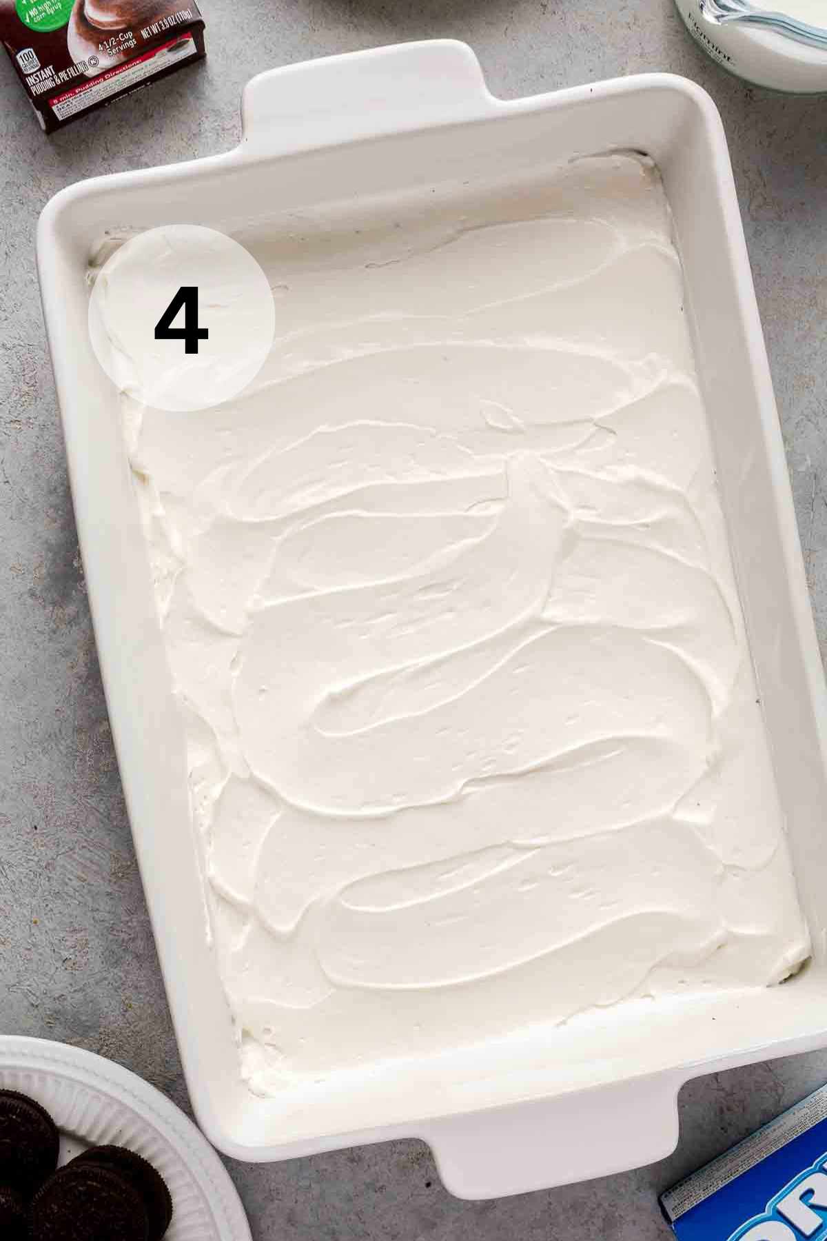 Cream cheese mixture spread in the bottom of a white casserole dish.