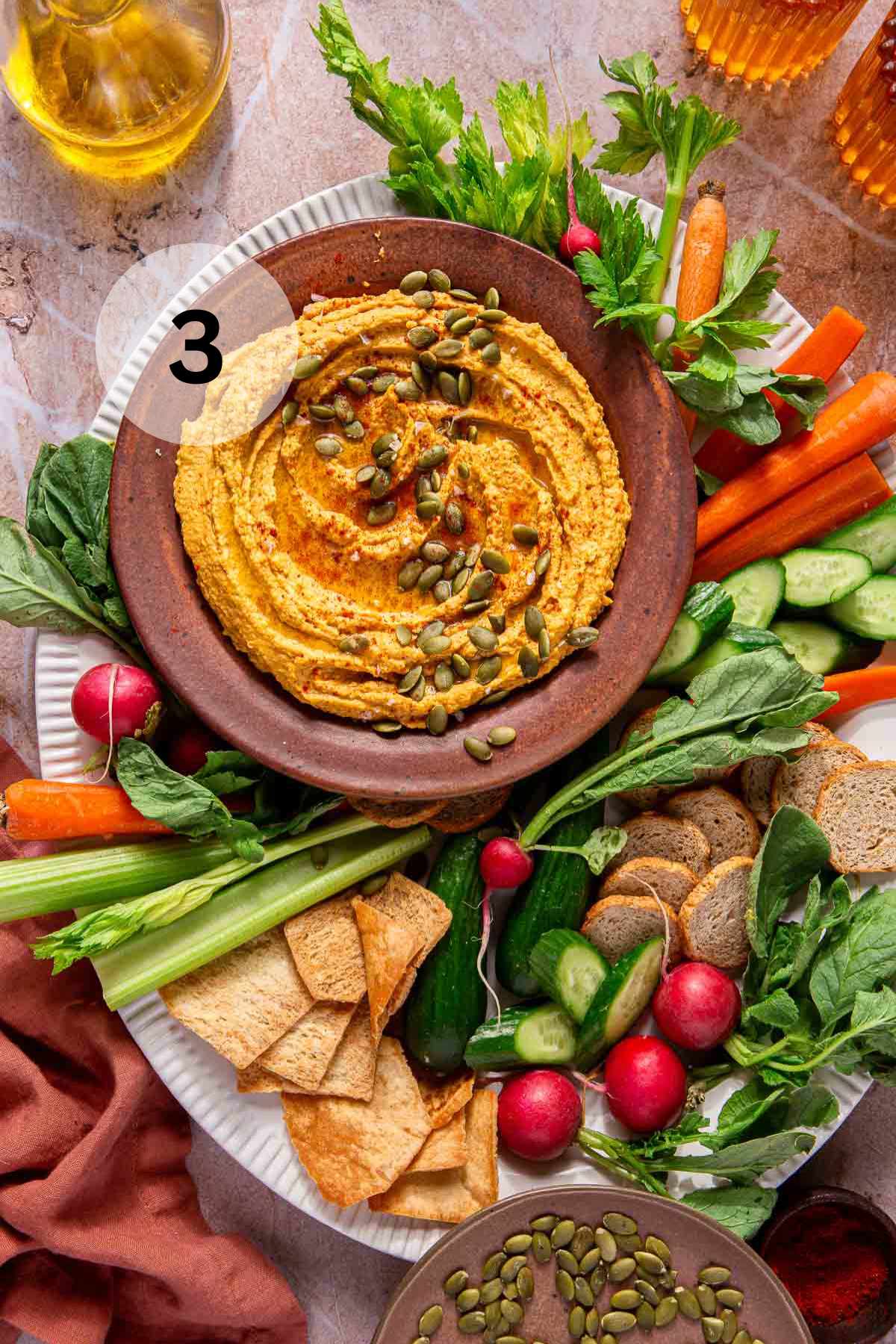 Pumpkin hummus served with crackers and fresh veggies.