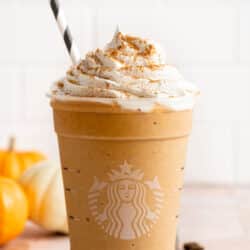 Pumpkin Spice Frappuccino topped with whipped cream and served with a straw.