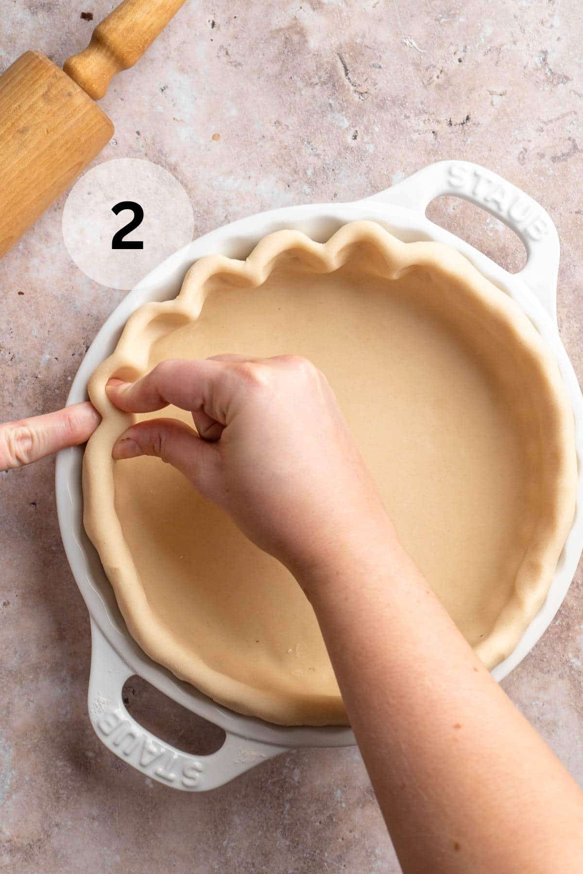 Using fingers and thumb to flute a pie crust around the edges.