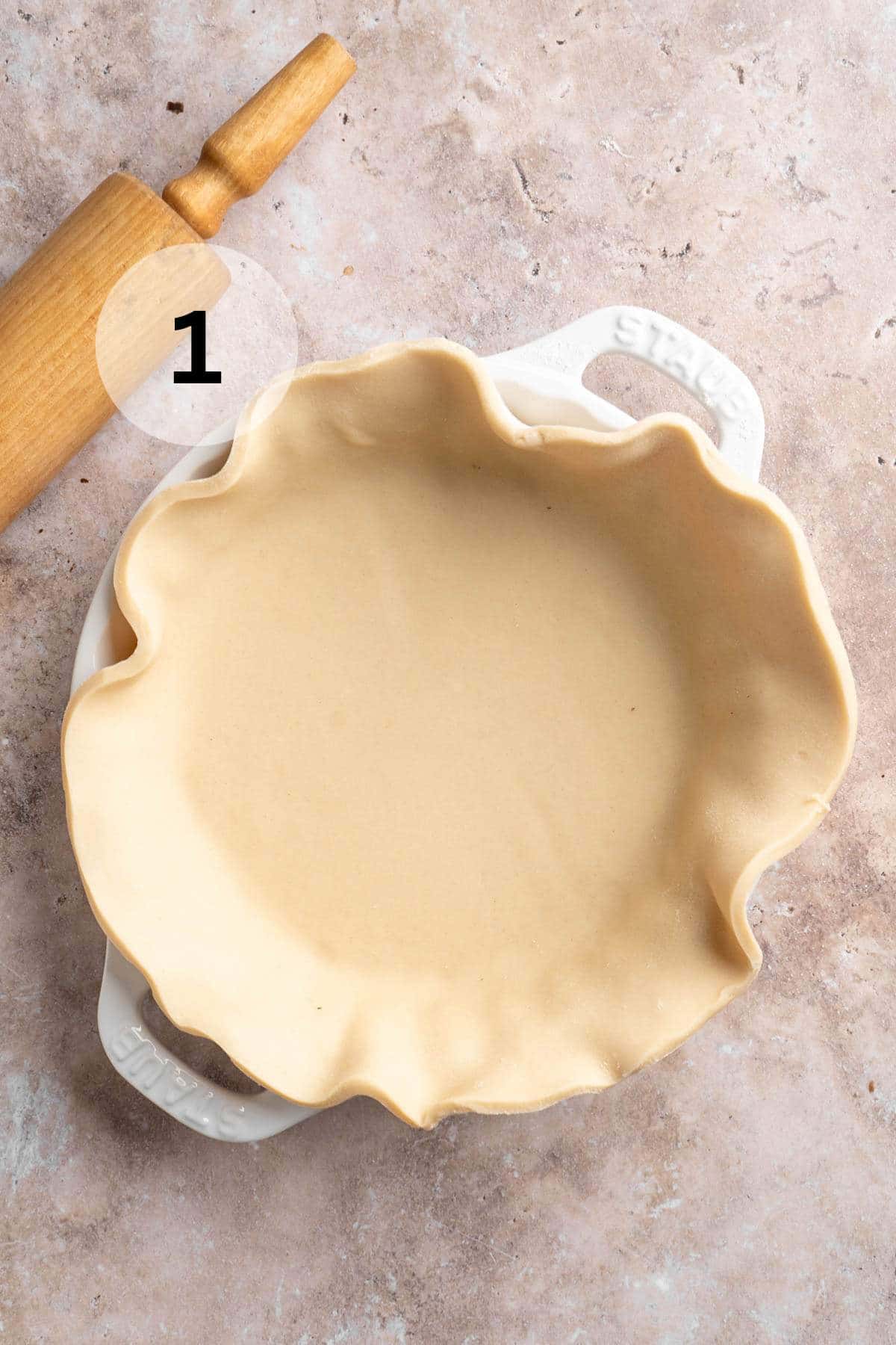 Pie crust draped over a white pie dish.