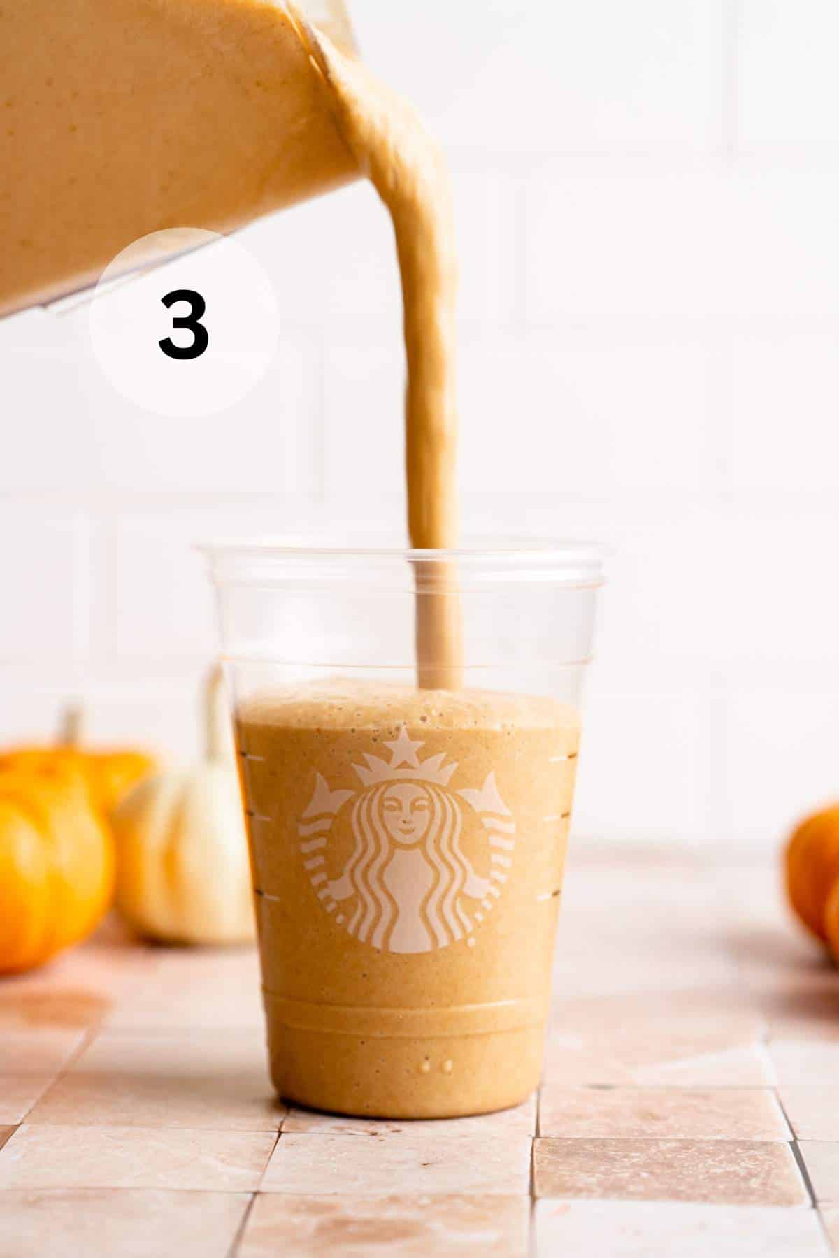 Pouring a pumpkin spice Frappuccino from a blender into a Starbucks cup.