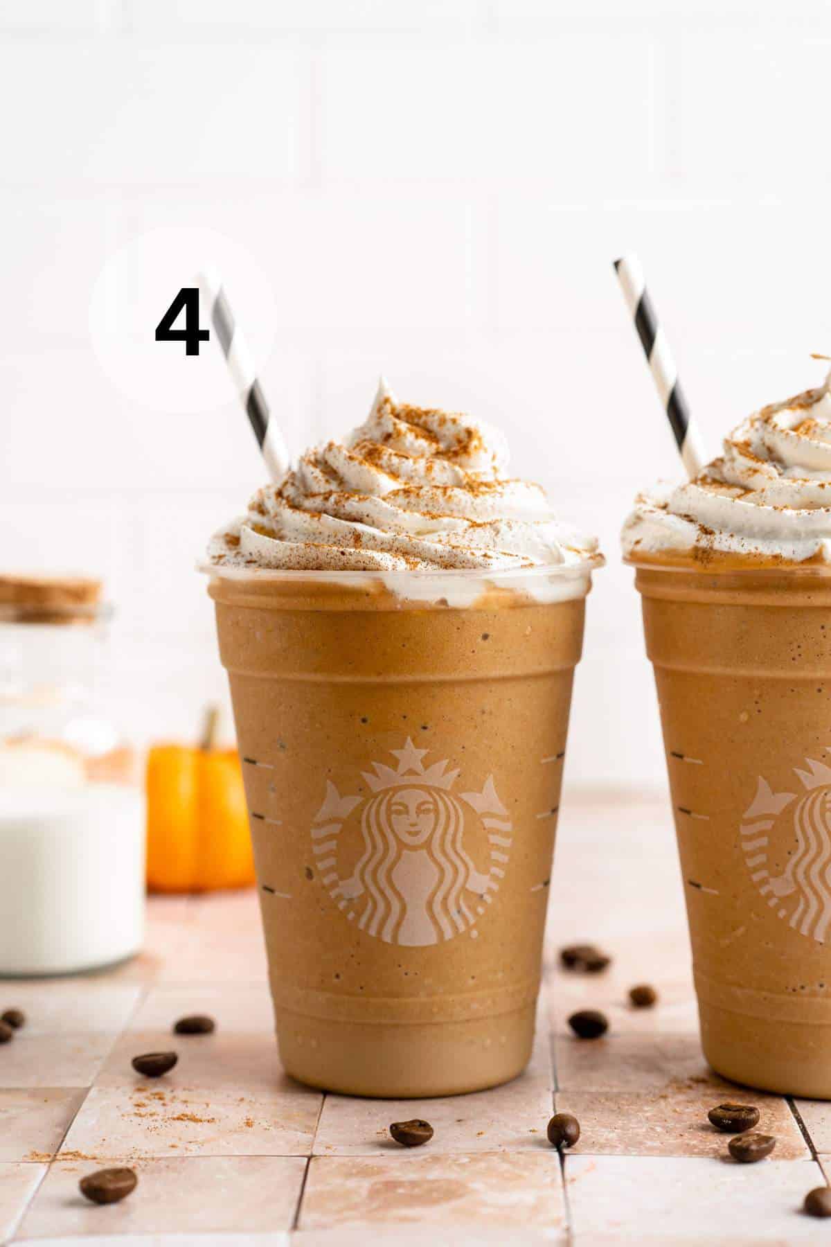 Two pumpkin spice Frappuccino drinks with whipped cream.
