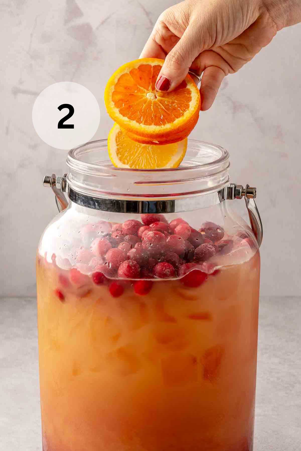 Adding orange slices to a punch mixture with cranberries.