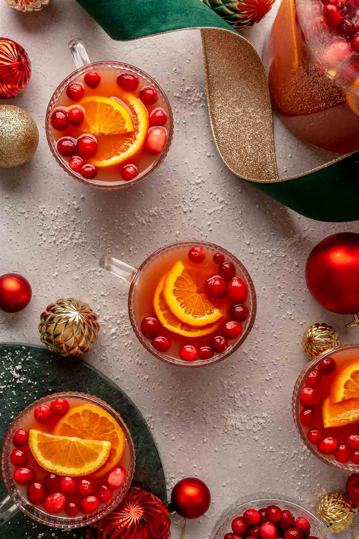 Small glasses filled with Christmas punch near ribbon and ornaments.