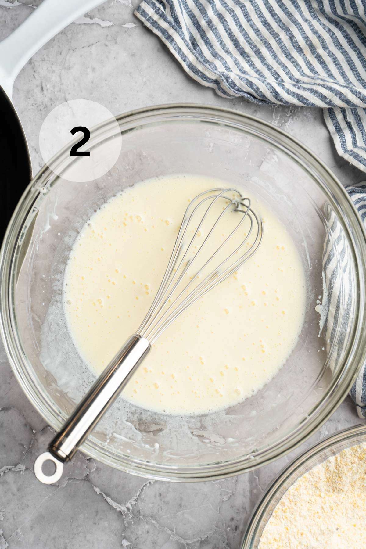 Whisking egg, milk and olive oil in a large glass bowl.