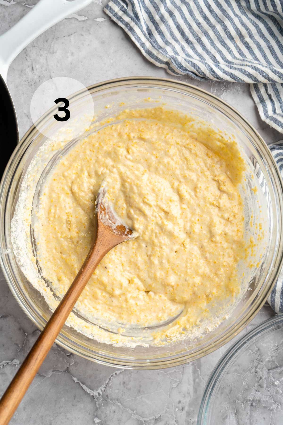 Using a wooden spoon to stir cornbread batter together.
