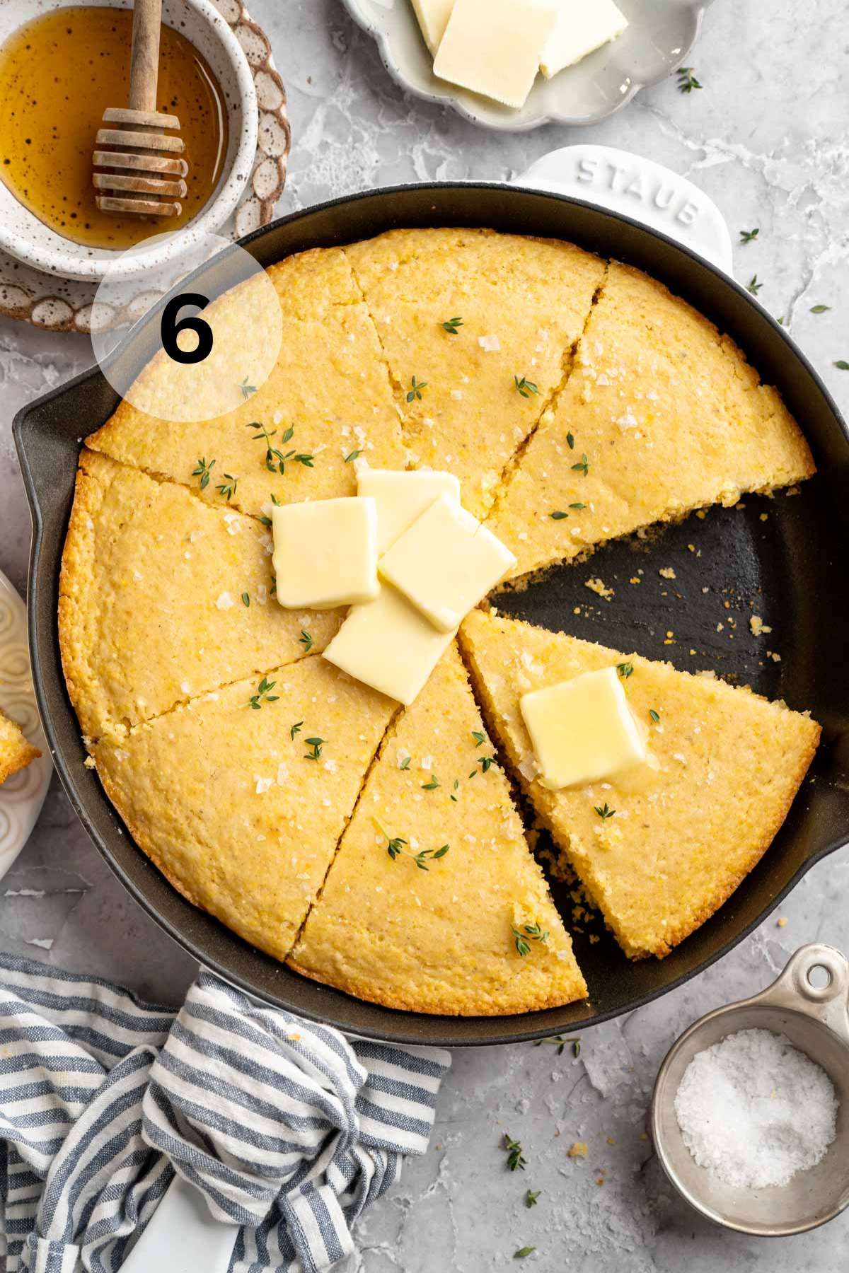 Cornbread in a skillet topped with butter.
