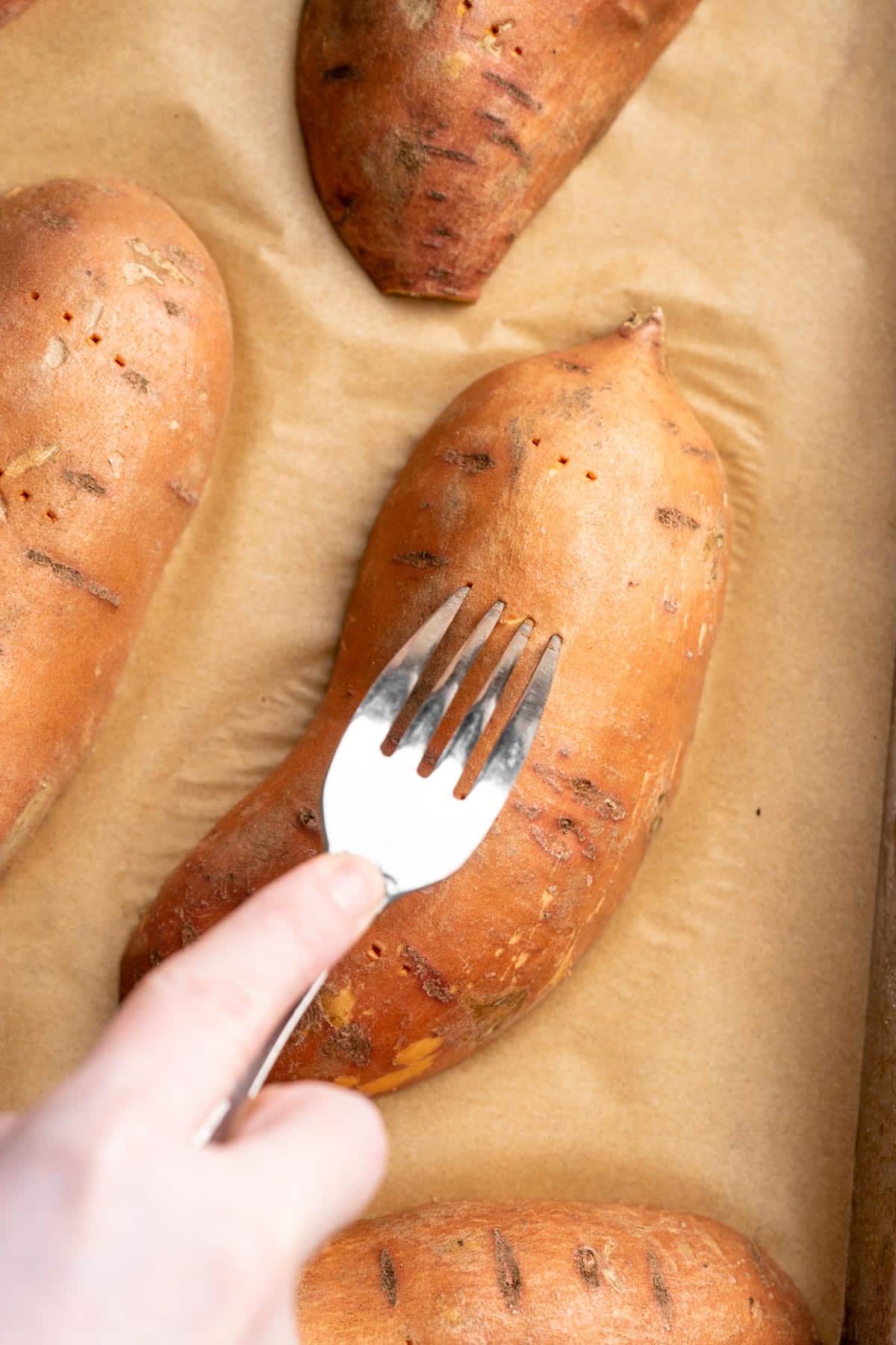 Using a fork to pierce the outside of a sweet potato.