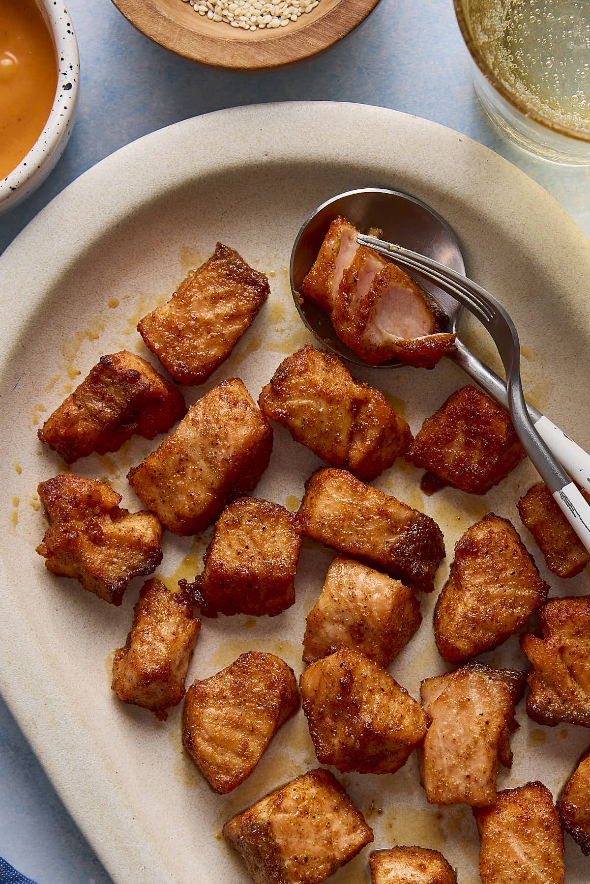 Air fryer salmon bites on a plate with a fork and spoon.