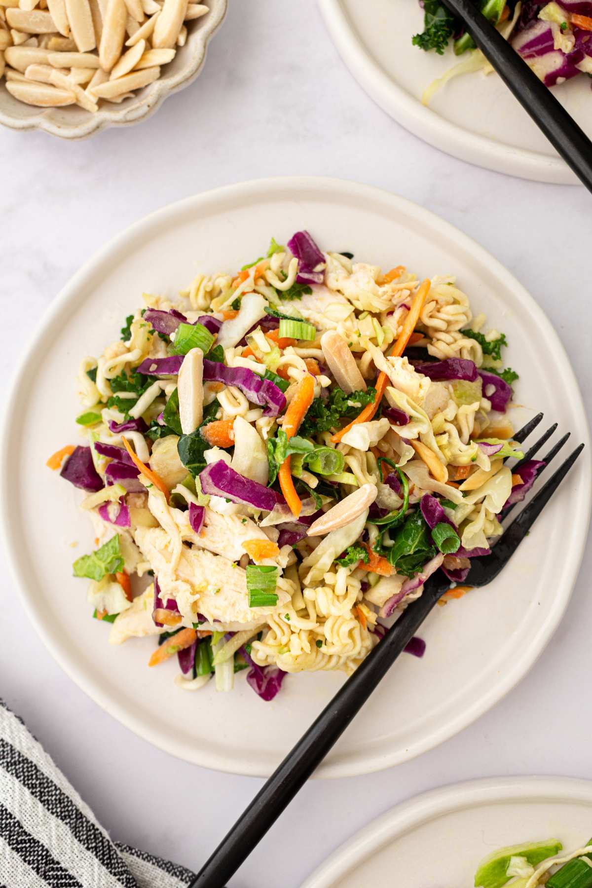 Ramen noodle salad on a white plate with a black fork.
