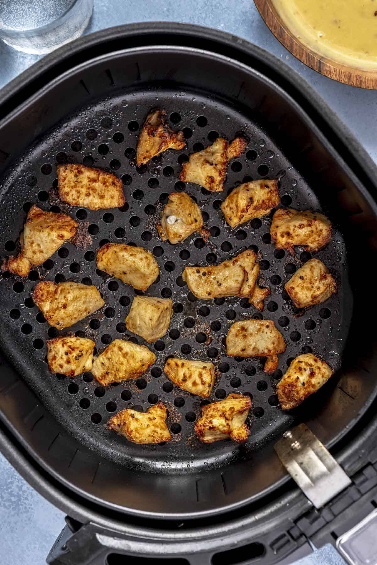 Air fryer chicken bites in an air fryer basket.