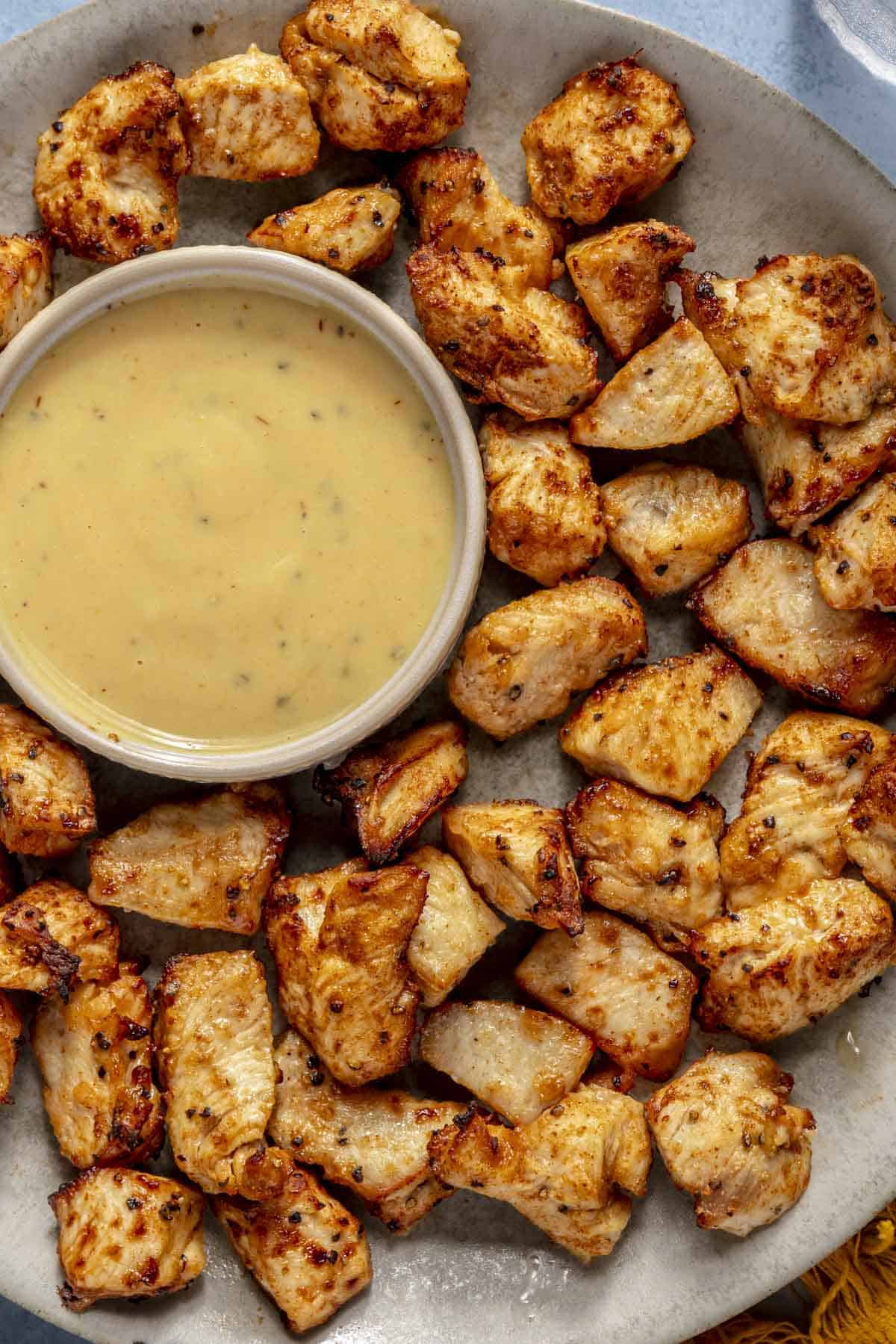 Air fryer chicken bites served on a plate with sauce.