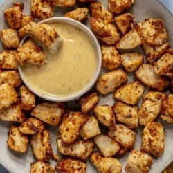 Air fryer chicken bites served with a small bowl of sauce.