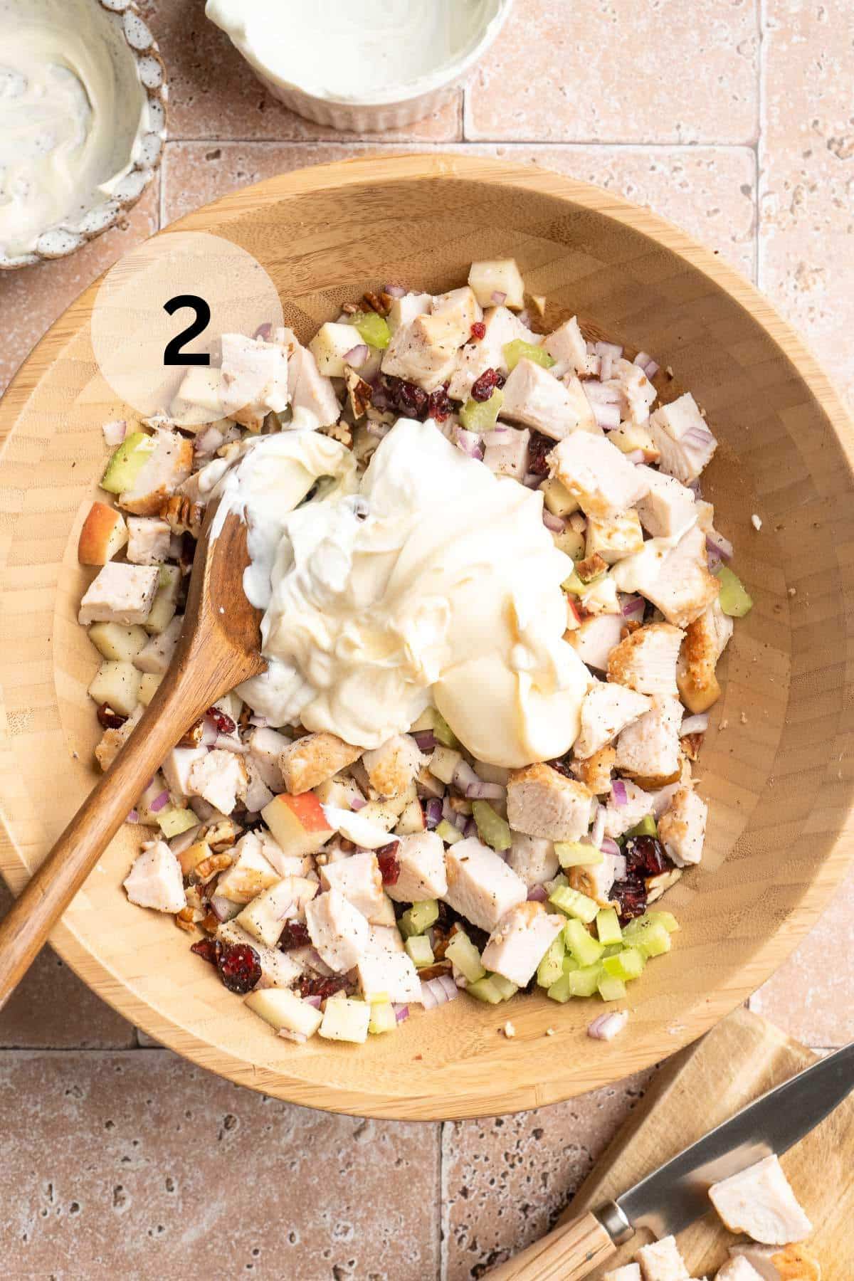 Adding mayonnaise and Greek yogurt to chicken salad mixture.