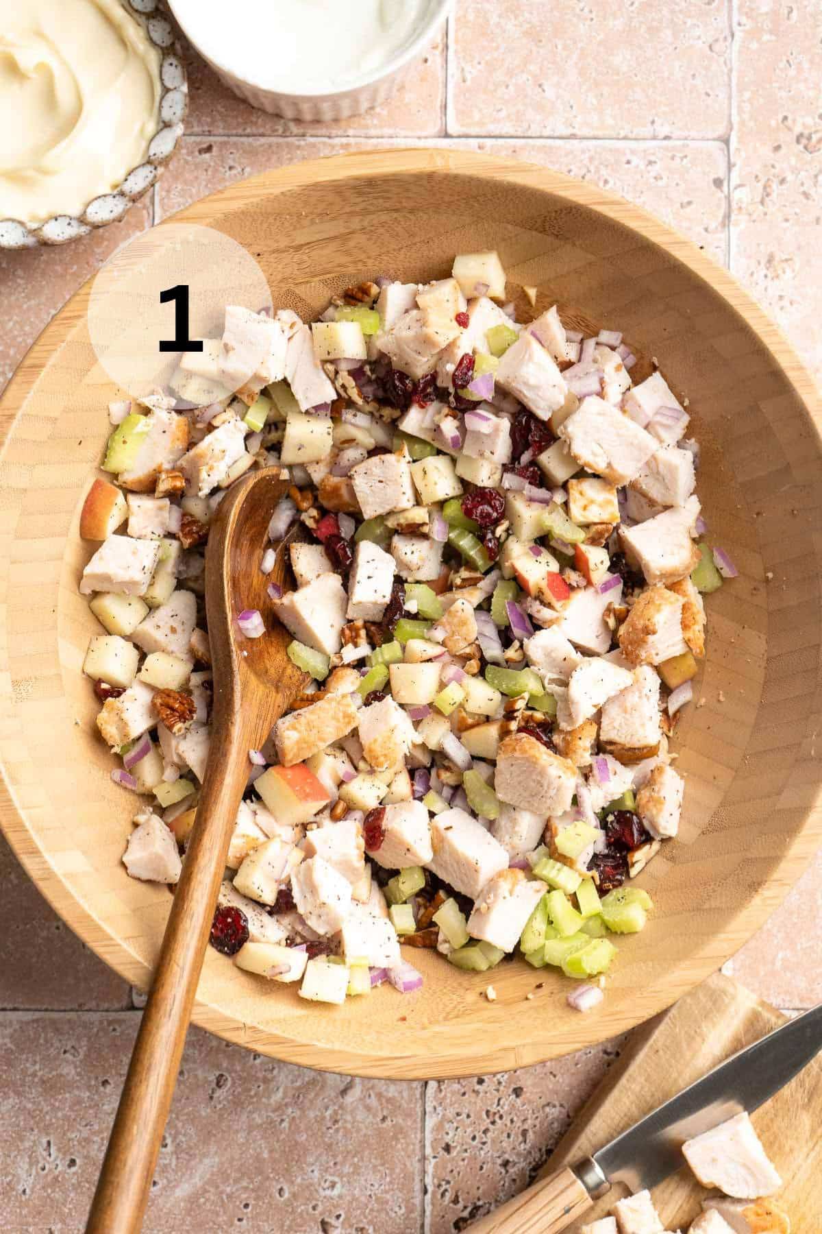 Combining cubed chicken with chopped apple, celery and onion.