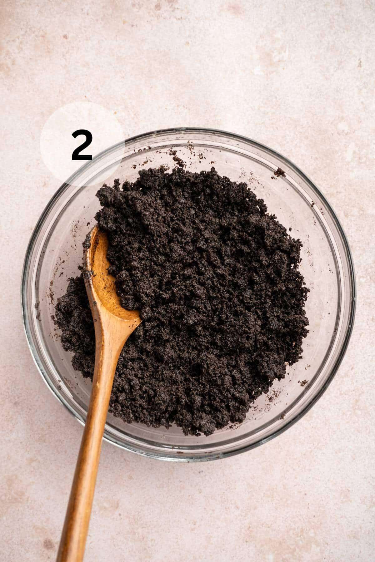 Stirring Oreo cookie crumbs with melted butter.