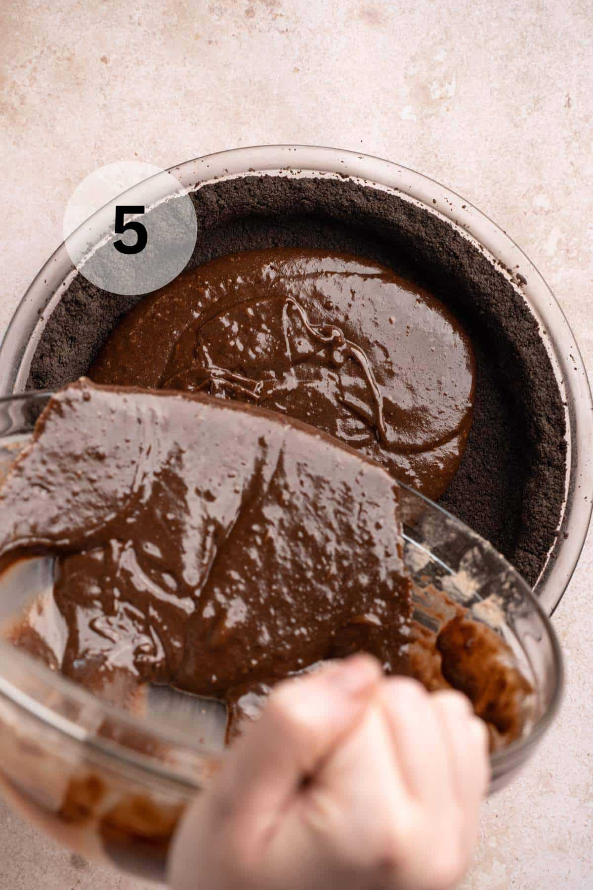 Pouring brownie batter into an Oreo crust.
