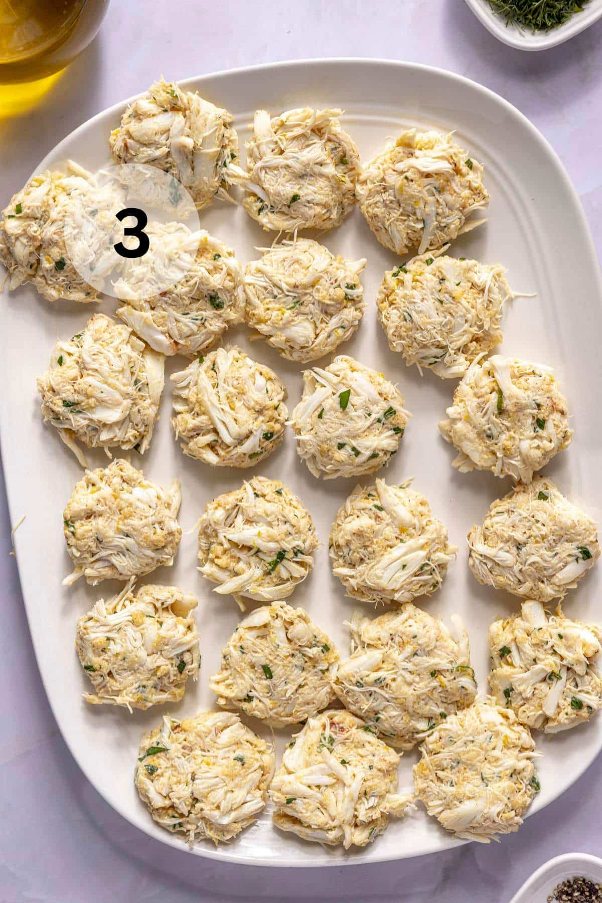 Formed crab cakes on a white tray.