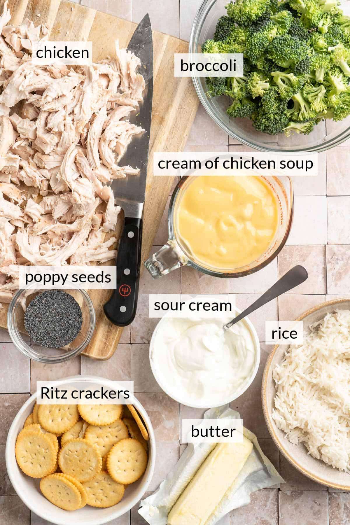 Shredded chicken on a cutting board near bowls of broccoli, sour cream, Ritz crackers and cooked rice.