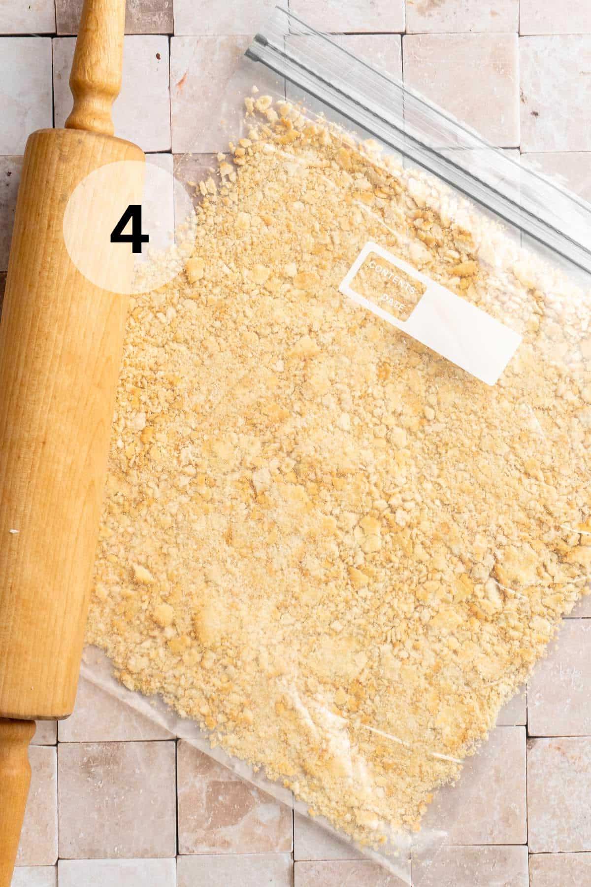 Crushed crackers in a bag near a rolling pin.