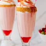 Strawberry milkshakes with a crushed graham cracker rim and whipped cream.