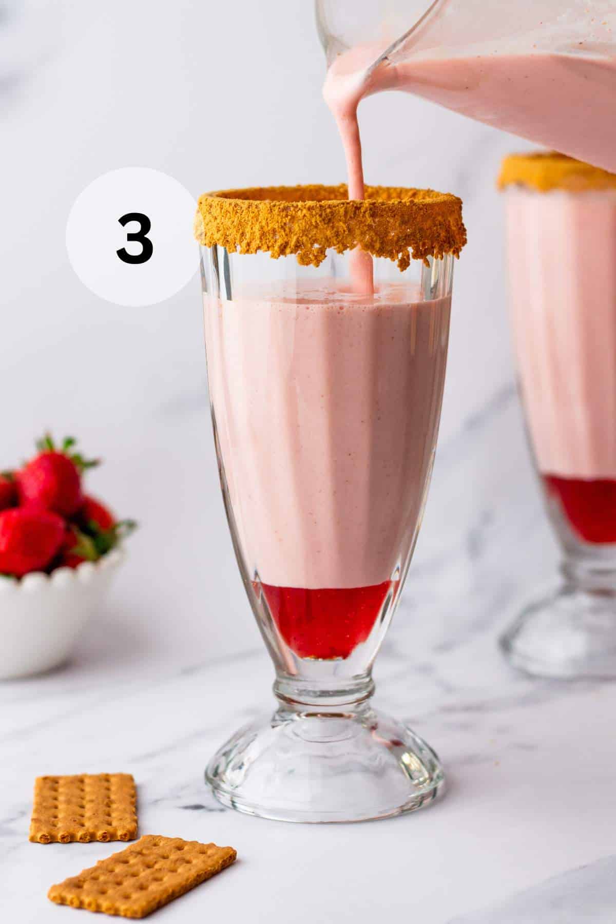 Pouring a strawberry milkshake into a milkshake glass.