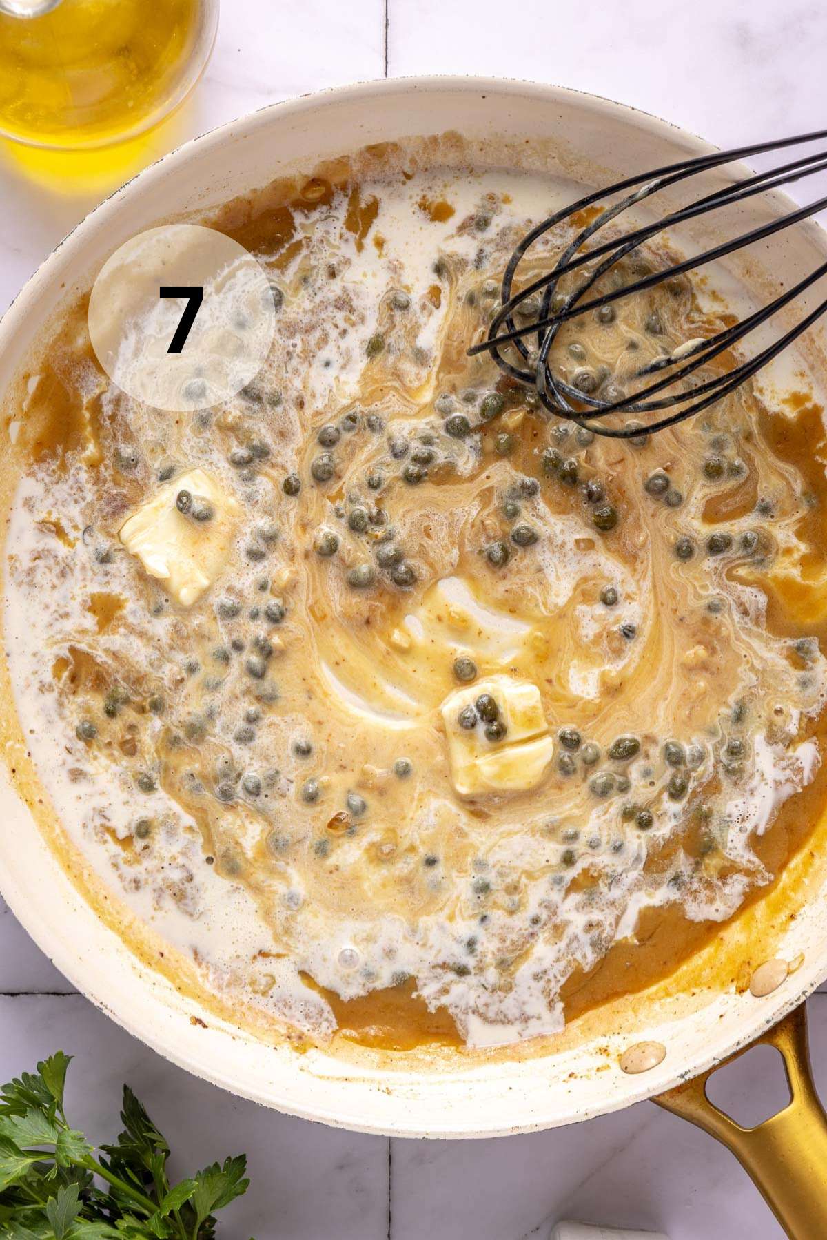 Whisking cream, butter and capers in a pan.