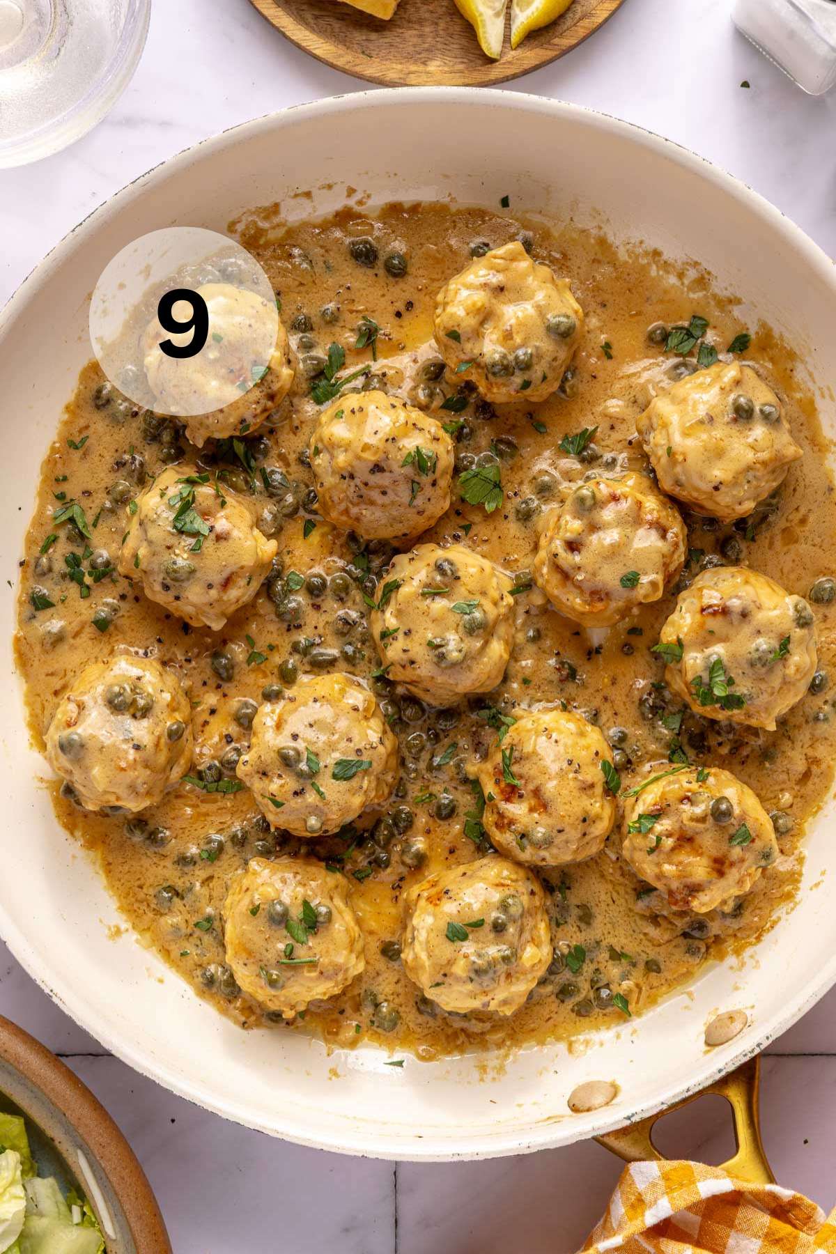 Chicken piccata meatballs garnished with fresh parsley in a large skillet.