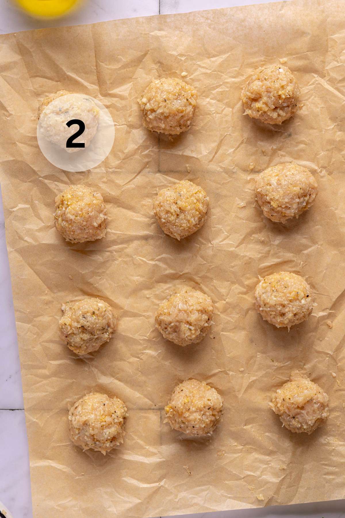 Raw chicken meatballs on parchment paper.