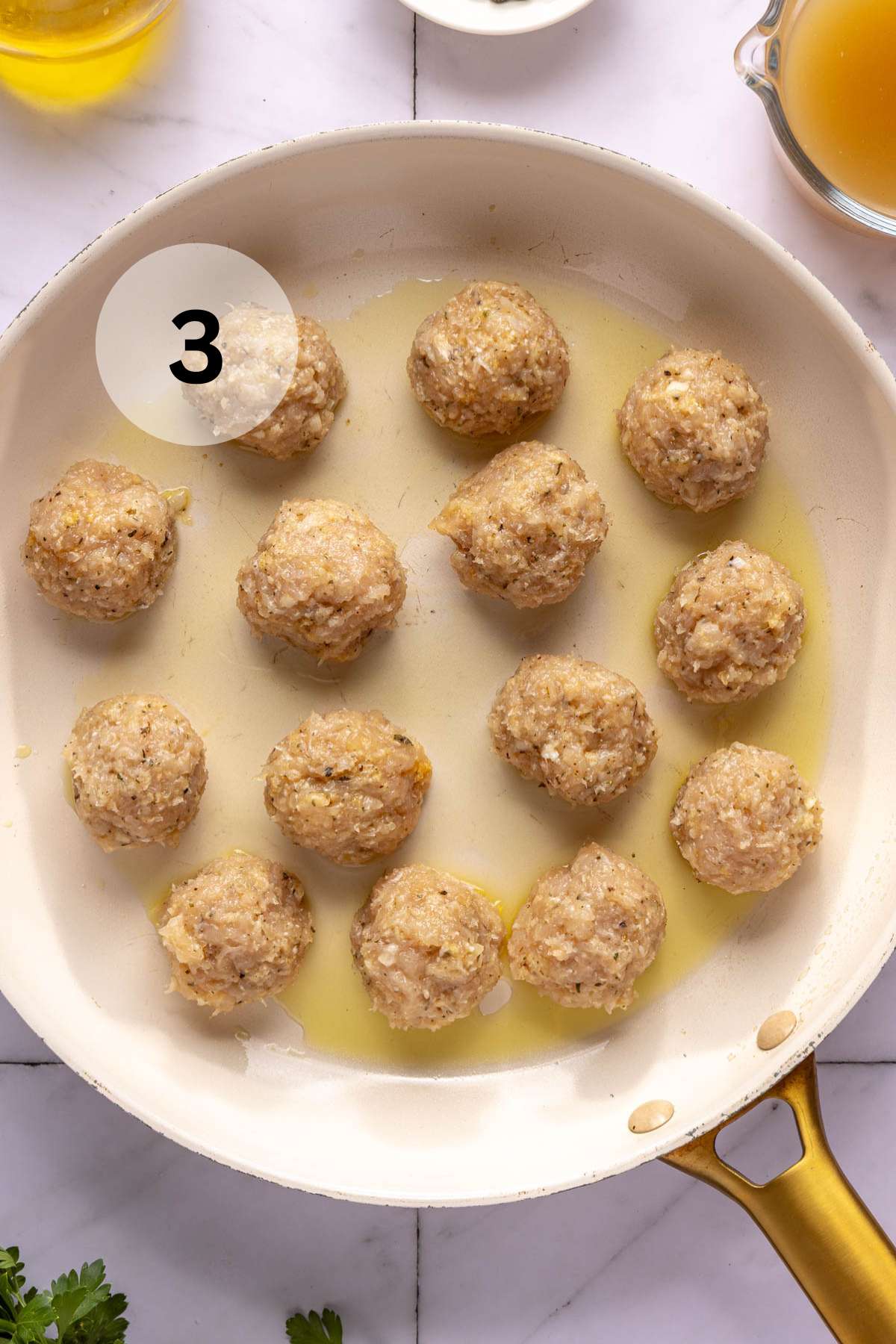 Meatballs cooking in a large skillet.