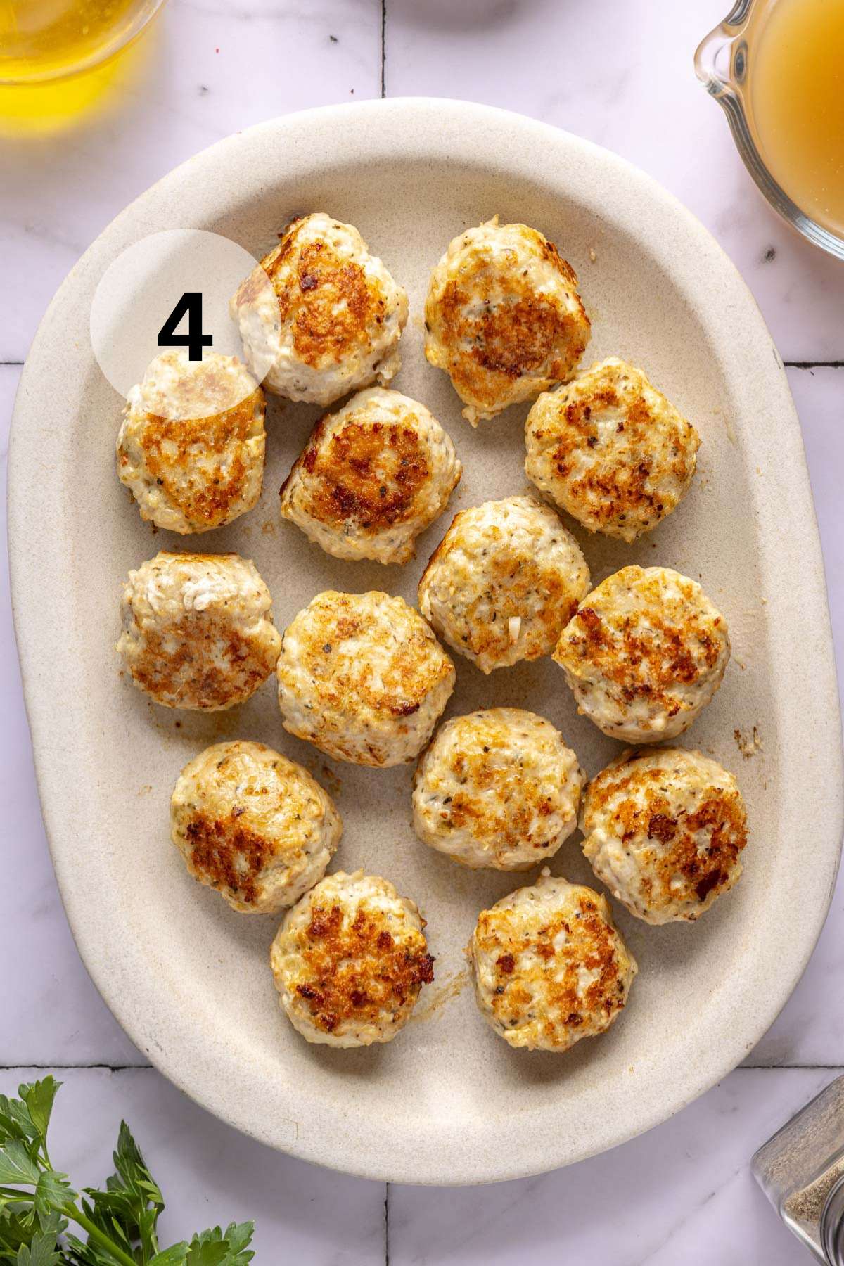 Cooked meatballs on a large white platter.